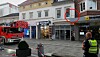 Einsatzfahrzeuge vor Geschäften, Polizist sichert die Straße ab.