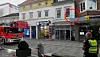 Einsatzfahrzeuge vor Geschäften, Polizist sichert die Straße ab.