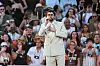 Bad Bunny singt im hellen Anzug vor jubelndem Publikum auf einer Konzertbühne.