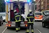 Einsatzkräfte beladen einen Rettungswagen auf einer Straße, im Hintergrund ein weiteres Einsatzfahrzeug.