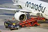 Koffer und Gepäckwagen an einem Marabu-Flugzeug am Flughafen Hamburg zur Verladung bereit.