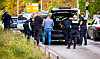 Polizisten durchsuchen Autos eines Hochzeitskorsos auf einer breiten Stadtstraße; die Braut wartet im weißen Kleid.