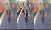 Zwei Personen gehen auf einem Bahnsteig neben einem Zug, im Hintergrund weitere Reisende.