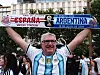 Argentinischer Fan hält Schal mit „España-Argentina“ und jubelt am Plaza de España in Madrid.