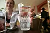 Junge Frau hält im Café CUP&CINO ein Glas Leitungswasser zum Espresso.