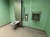 Barrierefreies WC mit Haltegriff und Hygienestation in einem mintgrünen Raum.