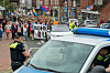 Polizisten sichern eine Demonstration mit Regenbogenfahnen und Transparenten auf einer Straße.