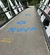 Fußgängerbrücke mit blauer und gelber Graffiti-Schrift und beschmierten Brüstungen.