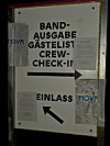 Aushang mit Band-Ausgabe, Gästeliste, Crew-Check-in und Einlass samt Pfeilen an einer Wand.