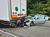 Pkw steckt nach Auffahrunfall unter Lkw, Trümmer liegen auf der Straße.