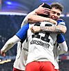 Zwei Fußballspieler umarmen sich nach einem Tor im Stadion, einer mit dem Schriftzug „KÖNIGSDÖRFFER“ auf dem Trikot.