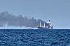 Frachter „Golden Leo“ auf dem Schwarzen Meer, dahinter steigt nach einem Angriff dichter Rauch auf.
