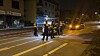 Polizeikräfte sichern nachts eine Straße ab, ein Wagen steht mit Licht daneben.