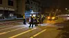 Polizeikräfte sichern nachts eine Straße ab, ein Wagen steht mit Licht daneben.
