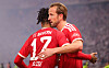Harry Kane und Michael Olise jubeln in roten FC-Bayern-Trikots nach dem 1:0 gegen Stuttgart.