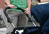 Person schiebt einen Kinderwagen mit dunkelblauem Bezug auf dem Gehweg.