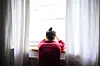 Person sitzt am Fenster und blickt hinaus – Sinnbild für den schweren Start nach dem Sommerurlaub.