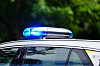Blaulicht auf dem Dach eines Polizeiautos vor grünem Hintergrund.