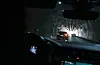 Blick aus dem Auto in einen Tunnel mit mehreren Fahrzeugen und Lichtkegeln.