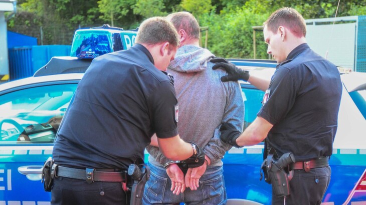 Polizisten führen einen Mann vor einem Streifenwagen am Lidl-Markt in Mümmelmannsberg ab.