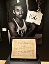 Wilt Chamberlain mit „100“-Schild und darunter ein signiertes Scorers Sheet bei Sotheby’s.