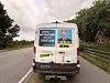 Weißer Transporter mit Wahlwerbung fährt auf einer Landstraße vorbei.