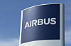 Airbus-Logo auf einem Schild am Werkseingang in Finkenwerder vor blauem Himmel.
