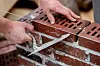 Maurer verlegt in Oldenburg einen Backstein auf einer Mauer.