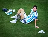 Lionel Messi sitzt enttäuscht auf dem Rasen im Stadion, Schuhe und Trinkflasche neben ihm.