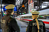 Zwei Polizisten beobachten einen vorbeifahrenden ICE in einer Bahnhofshalle.