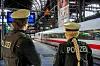 Zwei Polizisten beobachten einen vorbeifahrenden ICE in einer Bahnhofshalle.