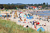 Menschen liegen und sitzen am Strand von Scharbeutz an der Ostsee bei sonnigem Sommerwetter.