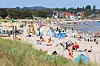 Menschen liegen und sitzen am Strand von Scharbeutz an der Ostsee bei sonnigem Sommerwetter.