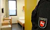 Justizbeamtin vor einer Zelle in der JVA Bremervörde; im Hintergrund ein karges Haftrauminterieur.