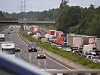 Autostau auf der Autobahn, Einsatzfahrzeuge und Lastwagen stehen am rechten Fahrbahnrand.