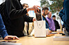 Kunden im Apple Store betrachten ein neues iPhone auf dem Tisch.