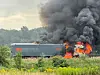 Lastwagen brennt am Feldrand, dichter schwarzer Rauch steigt auf, Flammen schlagen aus dem Fahrerbereich.