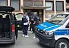 Bundespolizei vor Wohnhaus mit Einsatzfahrzeug und geöffneter Heckklappe am Eingang.