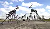 Filigrane Metallskulpturen auf Asphalt unter blauem Himmel, im Hintergrund wenige Menschen.