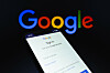 Smartphone mit Google-Anmeldeseite vor großem Google-Logo