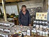 Verkäuferin an Marktstand mit Pralinen, Schokolade und Marmeladen in Gläsern.