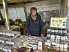 Verkäuferin an Marktstand mit Pralinen, Schokolade und Marmeladen in Gläsern.