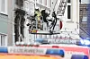 Feuerwehrleute in einem Korb einer Drehleiter, die Hauswand vor ihnen ist teilweise rußgeschwärzt.
