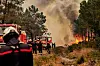 Feuerwehrleute und Löschfahrzeuge kämpfen in der Gironde gegen einen Waldbrand mit dichter Rauchwolke.