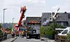 Leichtflugzeug steckt im Dach eines Hauses, Feuerwehr und Rettungskräfte sichern die Unfallstelle.
