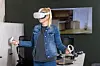 Person mit VR-Brille nutzt Handcontroller in einem modernen Raum.
