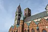 Dom von Ribe und Bürgerturm über roten Backsteinfassaden unter blauem Himmel.
