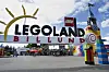 LEGO-Schriftzug am Eingang von Legoland Billund, daneben bunter Turm und leerer Vorplatz.