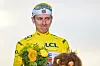 Tadej Pogačar im gelben Trikot auf dem Podium der Tour de France in Paris mit Blumenstrauß.