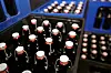Blaue Bierkästen mit dunklen Flaschen und weißen Verschlüssen in einem Lager.